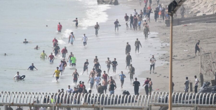 cientos de personas cruzan a nado a ceuta desde marruecos con una multitud esperando al otro lado de la frontera