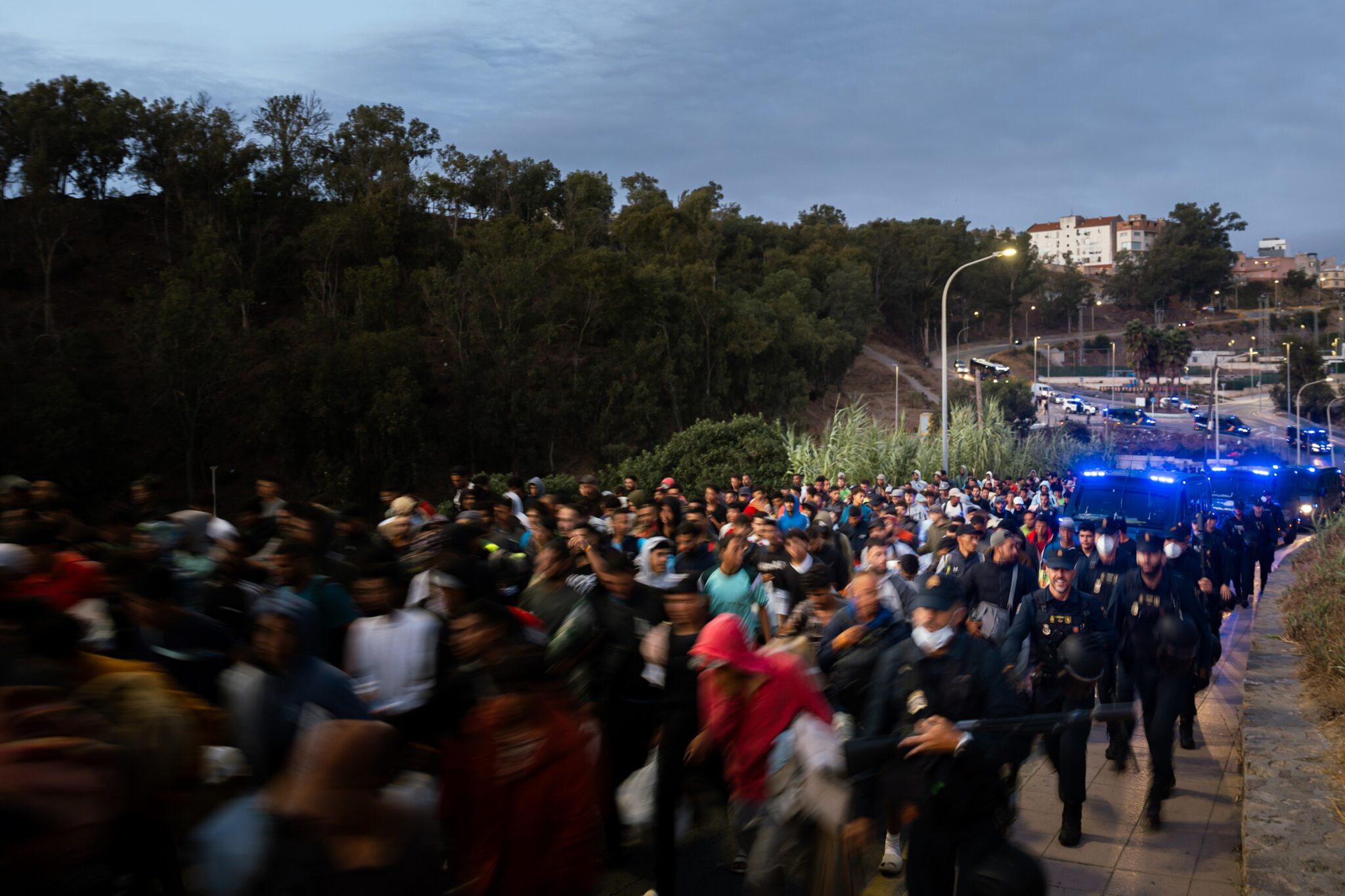 Centenares de personas se trasladan a pie durante el dispositivo de reubicación de migrantes hasta un nuevo centro tempo