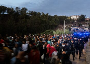 Centenares de personas se trasladan a pie durante el dispositivo de reubicación de migrantes hasta un nuevo centro tempo